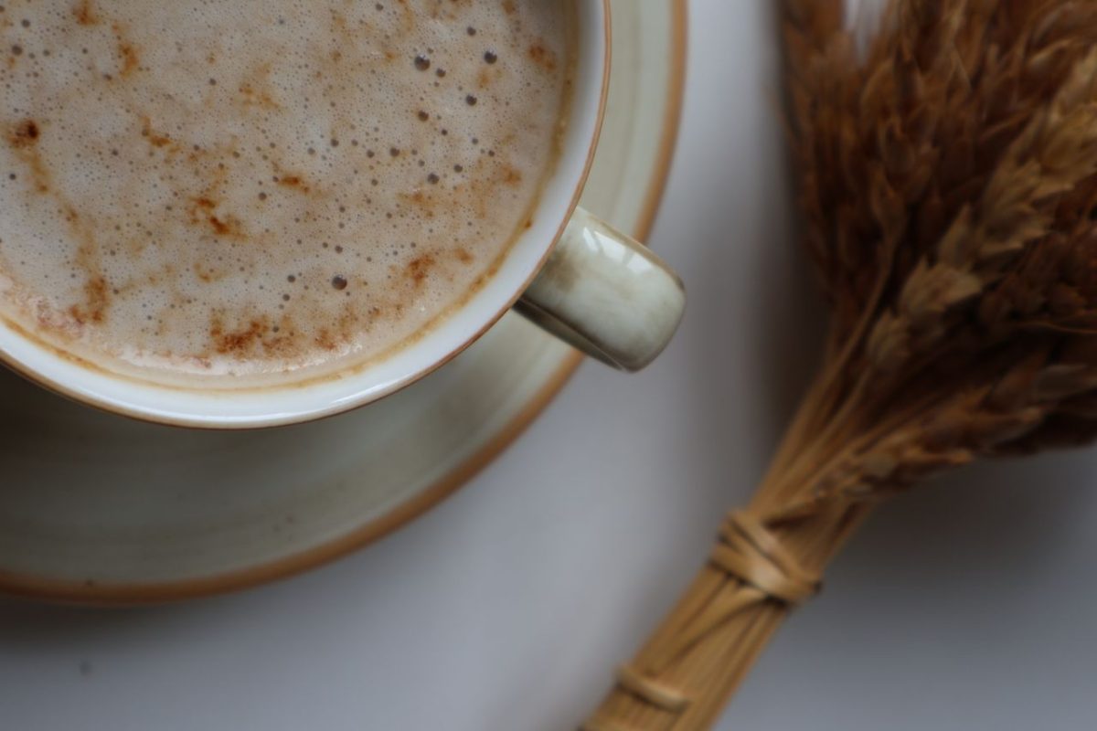 Cozy cup of coffee with wheat stalks on a rustic plate, perfect for fall-themed compositions.